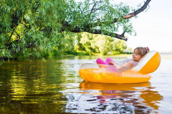 Niña se relaja en una silla inflable, flotando en el agua . — Foto de Stock