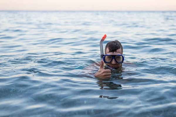 Ο άνθρωπος κολύμπι σε μια μάσκα για καταδύσεις και δείχνει ένα σημάδι περίπου. — Φωτογραφία Αρχείου