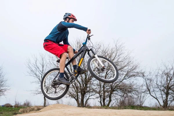 Hombre en una bicicleta de montaña realizando un salto de tierra . — Foto de Stock