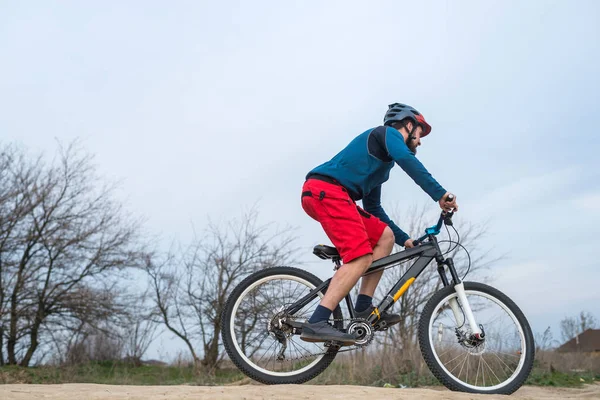 Rowerzysta w czerwonych spodenkach i niebieski sweter jeździ rowerem, aktywnym stylem życia. — Zdjęcie stockowe