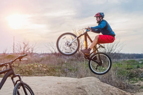 Un hombre en una bicicleta de montaña haciendo un salto de tierra. Estilo de vida activo . — Foto de Stock