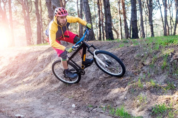 Ciclismo, un ciclista en ropa brillante montar una bicicleta de montaña a través del bosque. Estilo de vida activo . — Foto de Stock