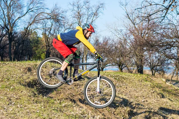Επαγγελματίας ποδηλάτης σε ένα κίτρινο πουλόβερ και κόκκινο shertakh οδηγώντας σε ένα λόφο, ελεύθερο χώρο. Ενεργός τρόπος ζωής. — Φωτογραφία Αρχείου