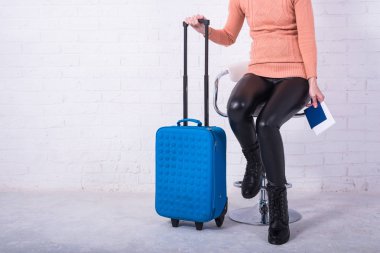 Mavi bavullu bir kadın sandalyede oturuyor, boş alan..