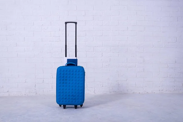 Blue suitcase near the white brick wall. — Stock Photo, Image