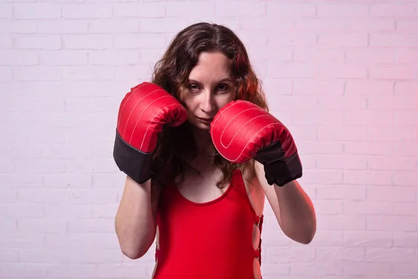 Mladá žena v červené boxerské rukavice na růžovém pozadí. — Stock fotografie