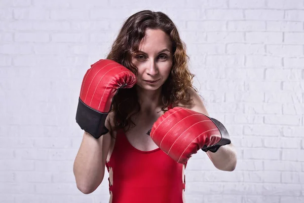 Mladá žena v červené boxerské rukavice na bílém cihlovém pozadí. — Stock fotografie
