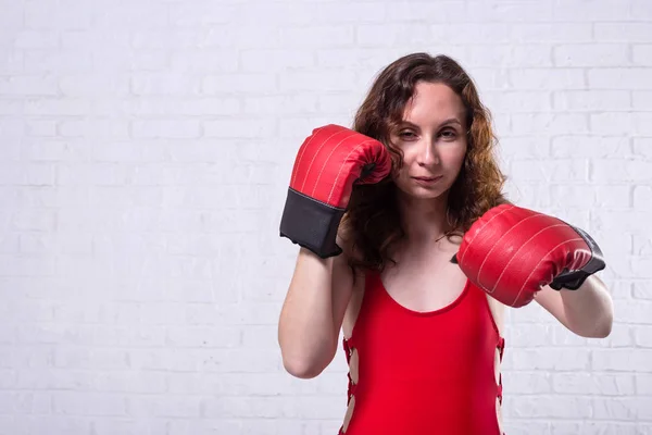 Mladá žena v červené boxerské rukavice na bílém cihlovém pozadí. — Stock fotografie