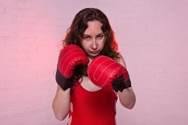 Mladá žena v červené boxerské rukavice na růžovém pozadí. — Stock fotografie