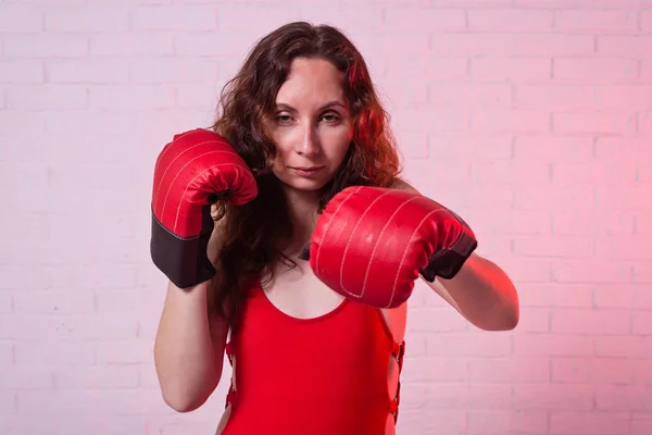 Mladá žena v červené boxerské rukavice na růžovém pozadí. — Stock fotografie