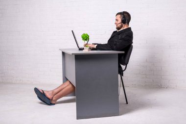 Bir dizüstü bilgisayarda bir konferans tutan bir takım elbise ve ev şort adam.