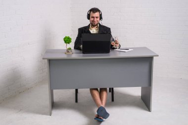 Bir dizüstü bilgisayarda bir konferans tutan bir takım elbise ve ev şort adam.