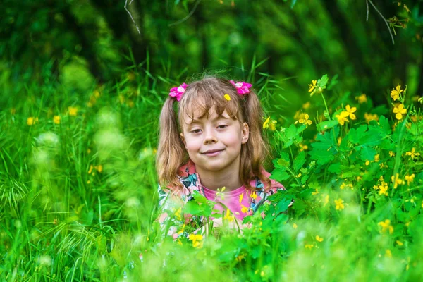 Mosolygós kislány körülbelül 6 év a háttérben a virágok. — Stock Fotó