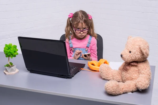 Linda niña en gafas trenzado en el teléfono inteligente . — Foto de Stock