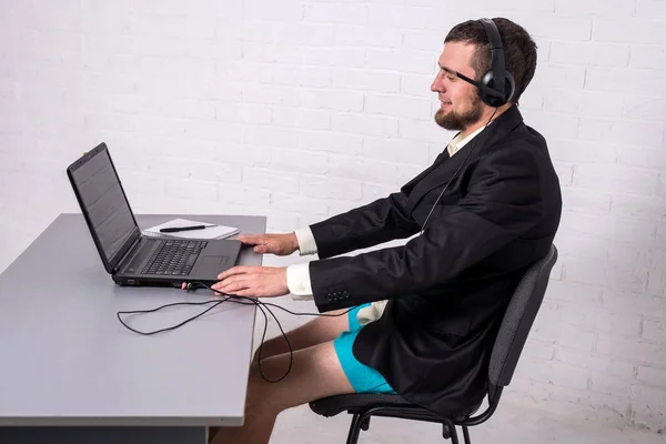 Man dressed in a suit and shorts siting with a laptop.