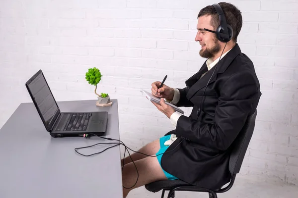 Man dressed in a suit and shorts siting with a laptop.