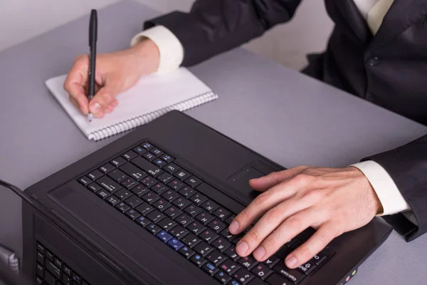 Empresario escribir en documentos en papel sobre los teclados del ordenador portátil . —  Fotos de Stock