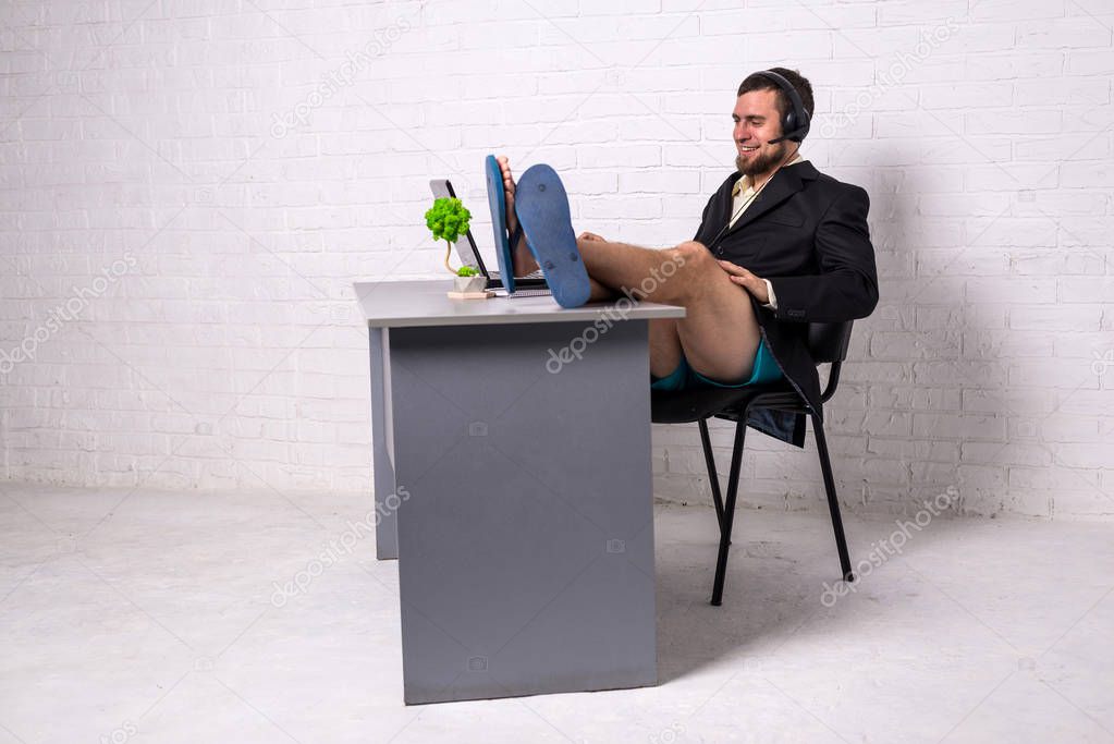 Man in a suit and home shorts holding a conference on a laptop computer.