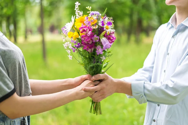 Young man giving flowers to girl bouquet closeup.