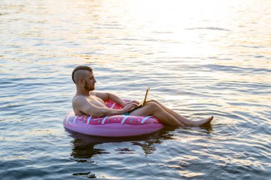 Su, boş alan üzerinde kauçuk şişme halka bir dizüstü bilgisayar ile İş adamı.