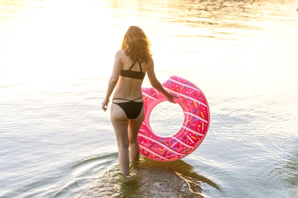 Mujer joven en un traje de baño está nadando en el anillo inflable . — Foto de Stock