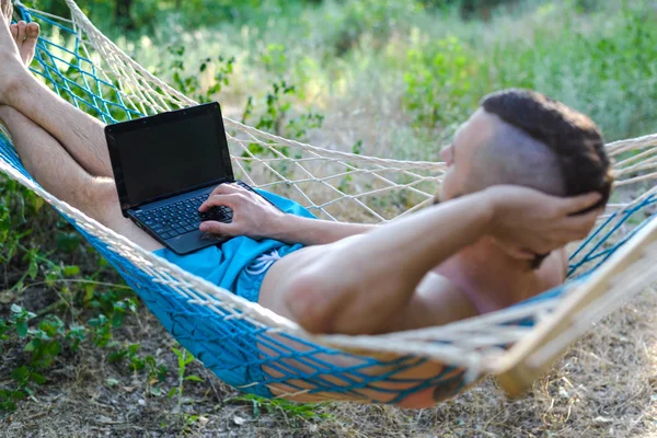 Freelancer trabajando en un portátil tumbado en una hamaca . —  Fotos de Stock