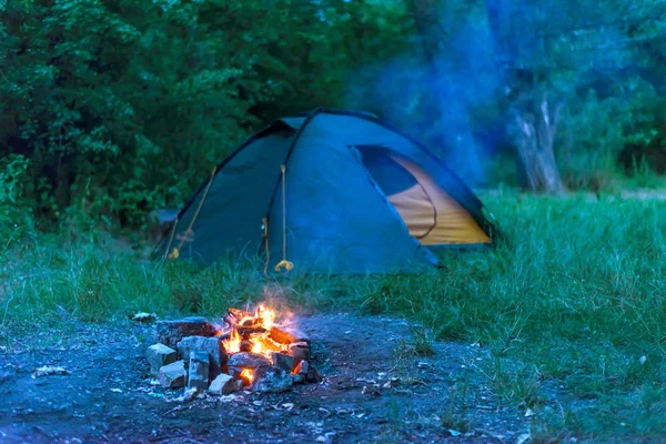 Tourist tent and fire in the forest, free space