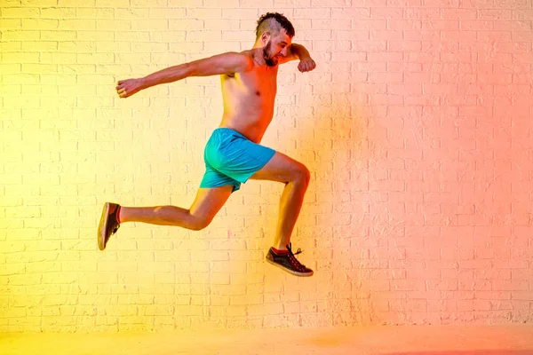 Joven deportista realiza un salto sobre un fondo amarillo . — Foto de Stock