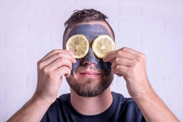 Uomo che mette una maschera di argilla sul viso su un ritratto di sfondo nero . — Foto Stock