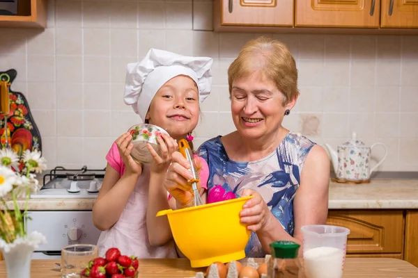 Grandmother and little granddaughter prepare the dough for the cake. — Stock Photo, Image