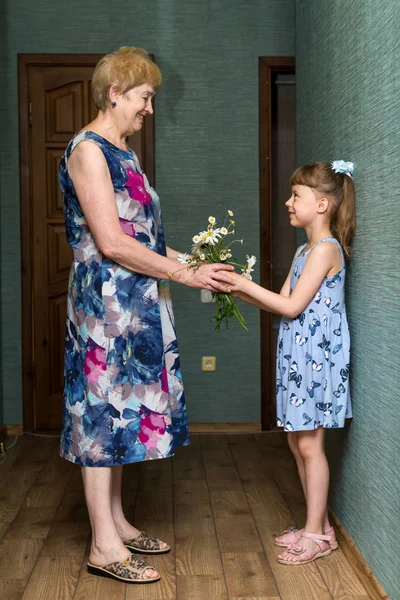 Granddaughter giving a grandmother a bouquet of daisies. — Stock Photo, Image
