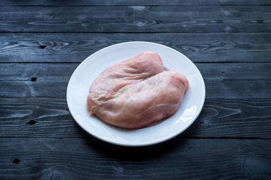 Siyah ahşap bir masa üzerinde çiğ tavuk göğsü, üst görünümü.