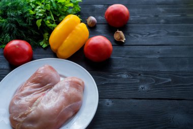 Ahşap bir masada çiğ tavuk ve sebze, boş alan.