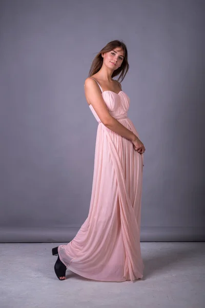 Young girl in a pink dress posing on a gray background. — Stock Photo, Image