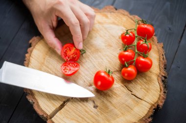 Şef tahta bir tahta üzerinde kiraz domates dilimleme, yakın çekim.