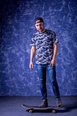 Mavi arka plan üzerinde bir kaykay üzerinde duran kaykaycı.