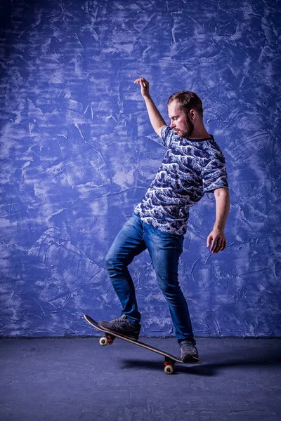 Patinador de pie en un monopatín sobre un fondo azul. Ollie. . — Foto de Stock