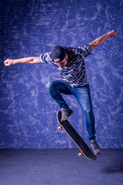 Skateboarder realizando un salto de altura sobre fondo azul. Ollie. . — Foto de Stock