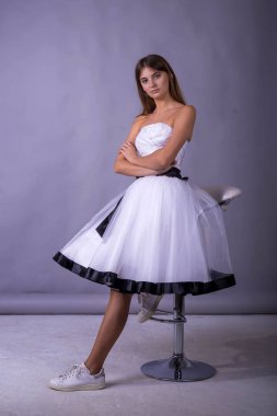 gri zemin üzerine beyaz elbiseli genç güzel kadın modeli