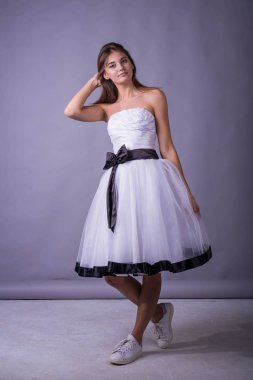 gri zemin üzerine beyaz elbiseli genç güzel kadın modeli.