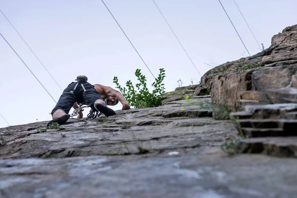 Dolní pohled na mladého horolezce visícího na skále, volný prostor. — Stock fotografie