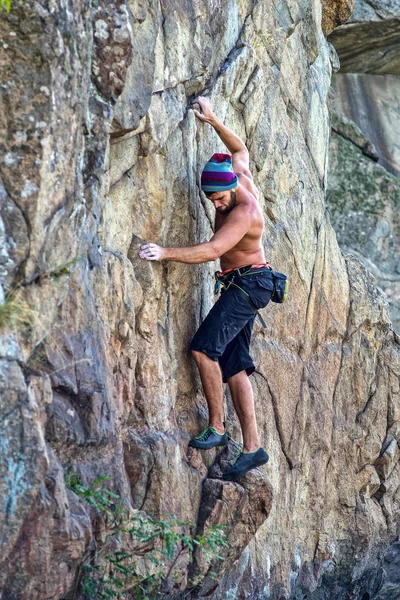 Vista lateral de un joven escalador colgado en una roca, espacio libre . — Foto de Stock