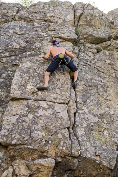 Escalador de rocha sobe uma parede de pedra, vista traseira . — Fotografia de Stock