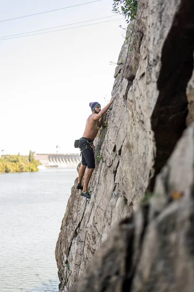 Hombre escalador subiendo a la cima de la roca . — Foto de Stock