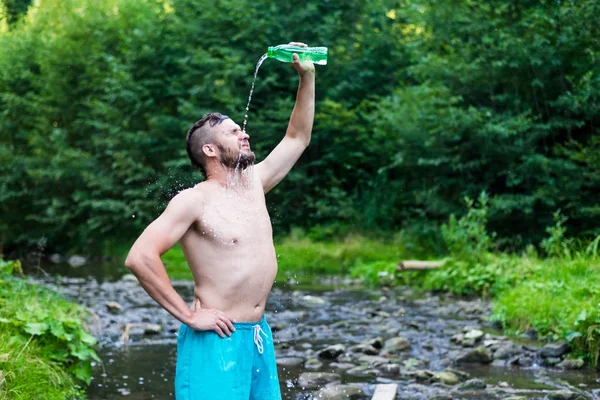 Snygg sportig man uppfriskande själv med vatten efter träning utomhus — Stockfoto