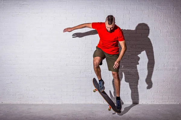 Skateboarder saltar ollie en un monopatín en el fondo de una pared blanca . — Foto de Stock