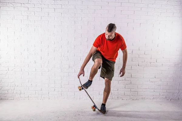 Skateboarder saltar ollie en un monopatín en el fondo de una pared blanca . — Foto de Stock