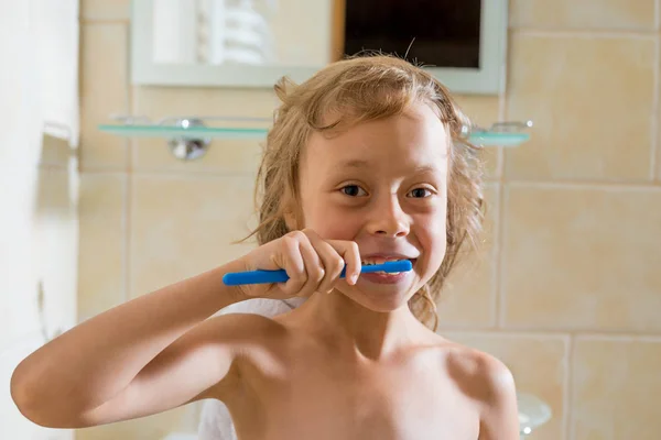 Cute adorable toddler girl holding toothbrush and brushing first teeth in bathroom after sleeping.