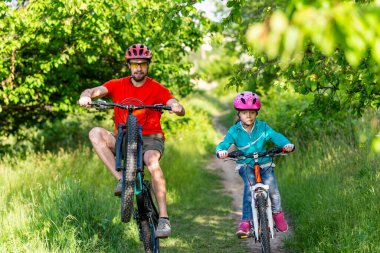 Baba ve kızı bisiklet sürüyorlar, aktif bir yaşam tarzı. Okul tatili. Aktif aile.