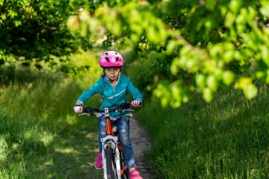 9 yaşlarında küçük bir kız bisiklete biniyor. Aktif yaşam tarzı. Okul yaz tatili.